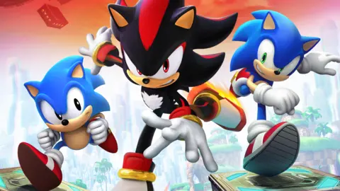 Sega Sonic, karakter kartun landak maskot biru, berlari ke arah penonton. Di sampingnya ada Sonic versi lama, serta Shadow, karakter landak hitam.